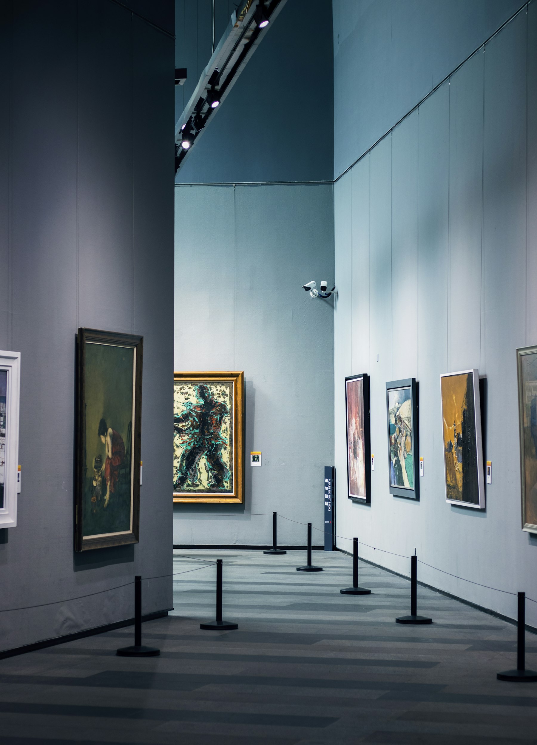A quiet gallery hung with paintings in low light.