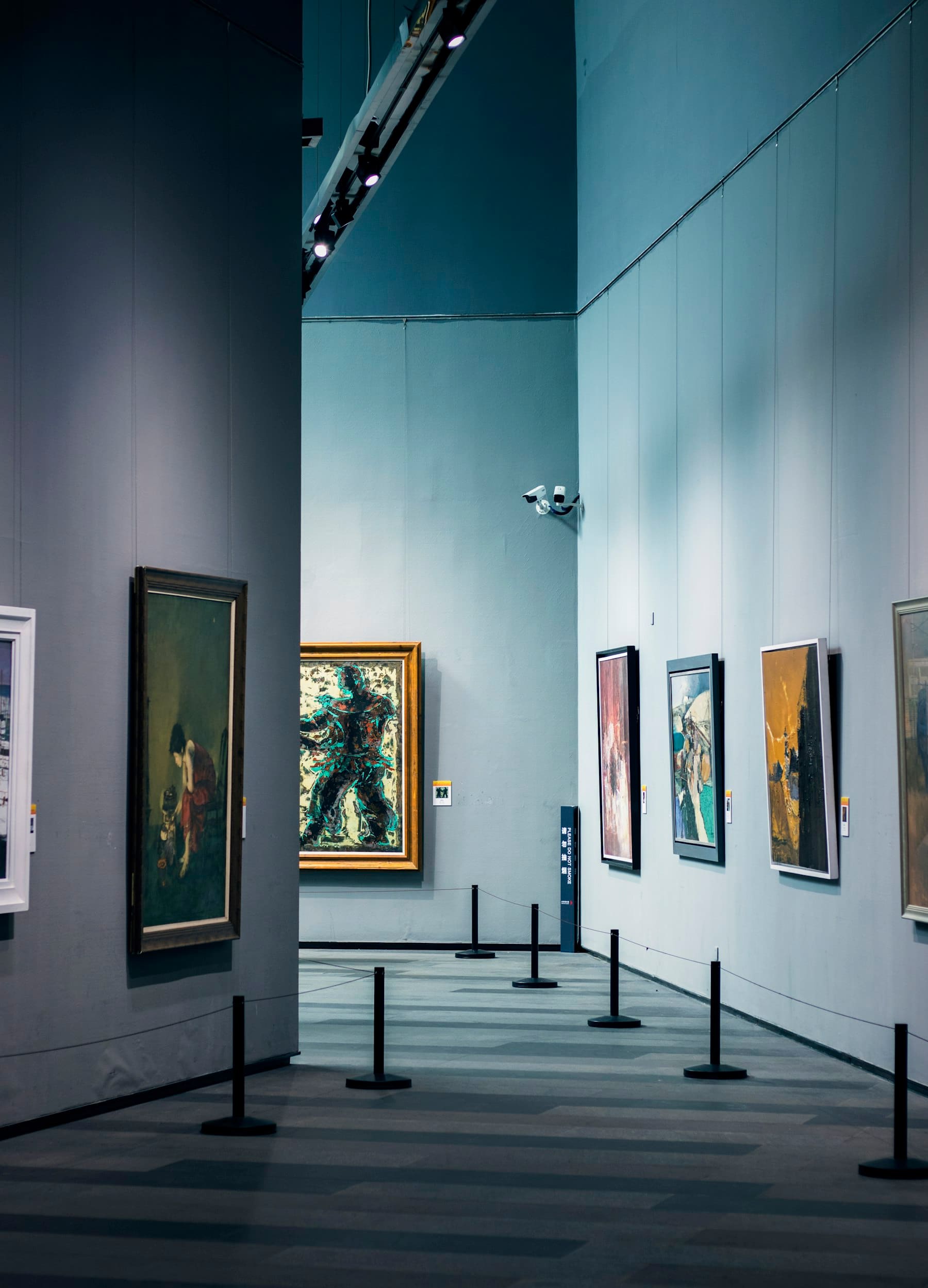 A quiet gallery hung with paintings in low light.